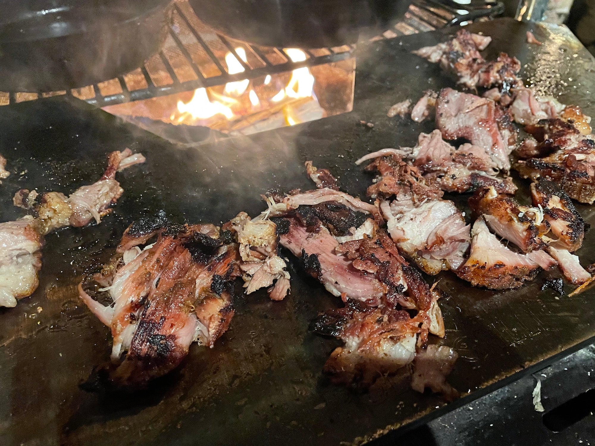 Pork roasting on the roasting plate accessory above a hot fire.