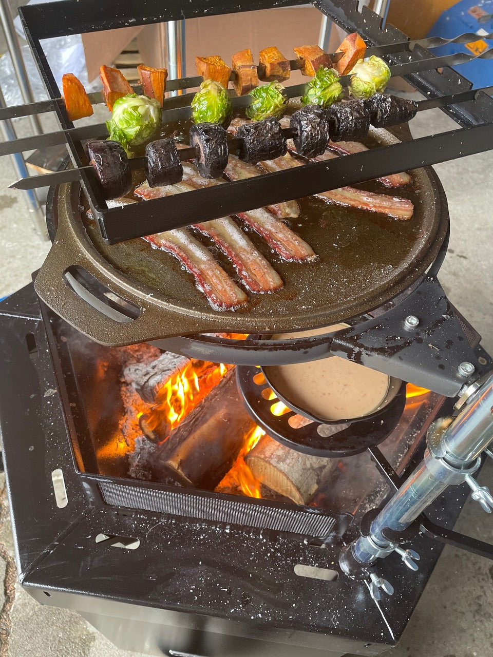     Sweet Potato, Brussel Sprouts and Mushroom sit skewered above searing bacon and tortilla in a separate pan.   