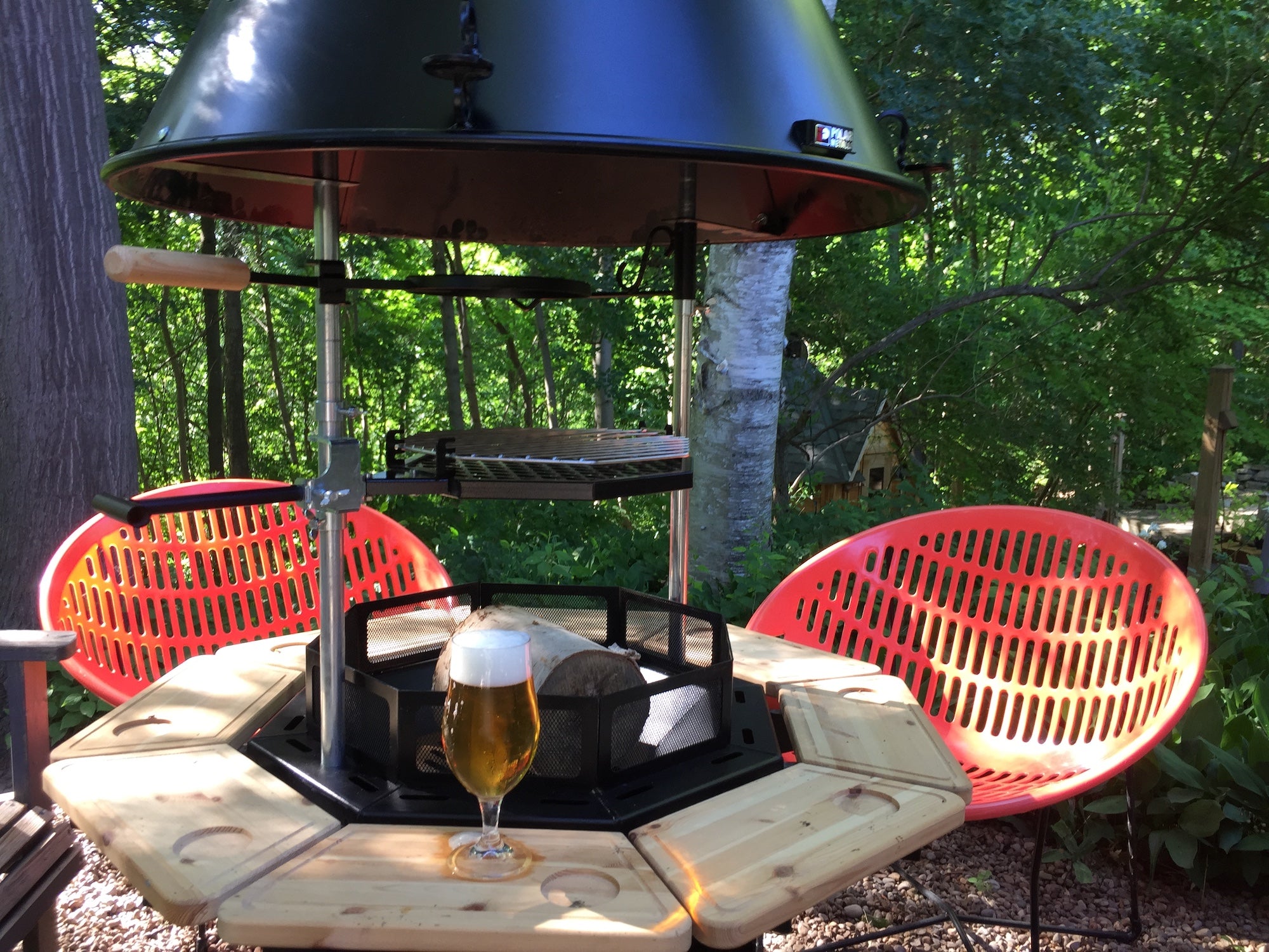  A tall glass of beer sits infront of an S8 Kota Grill in a backyard with bright orange chairs in the background.      